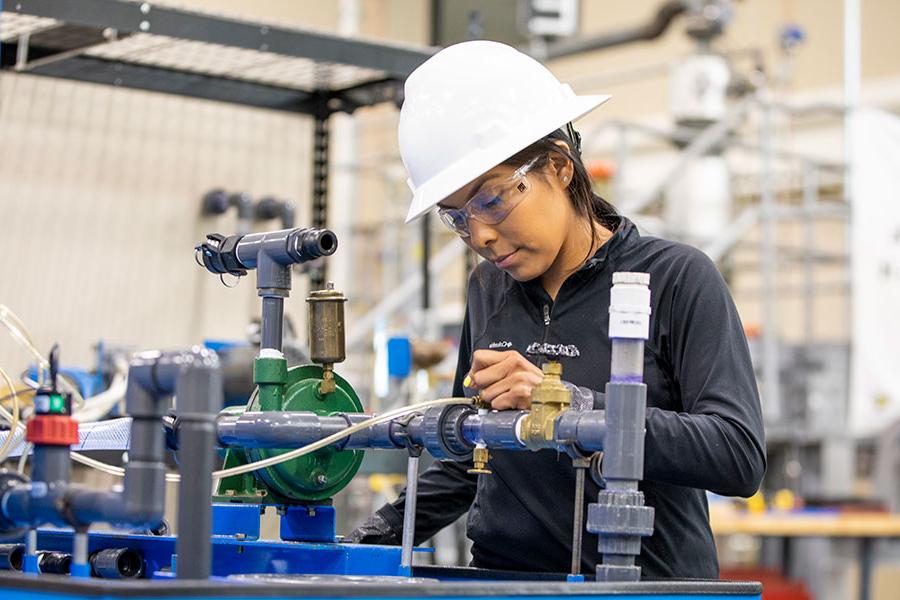 An individual in a hard hat inspects valves and equipment